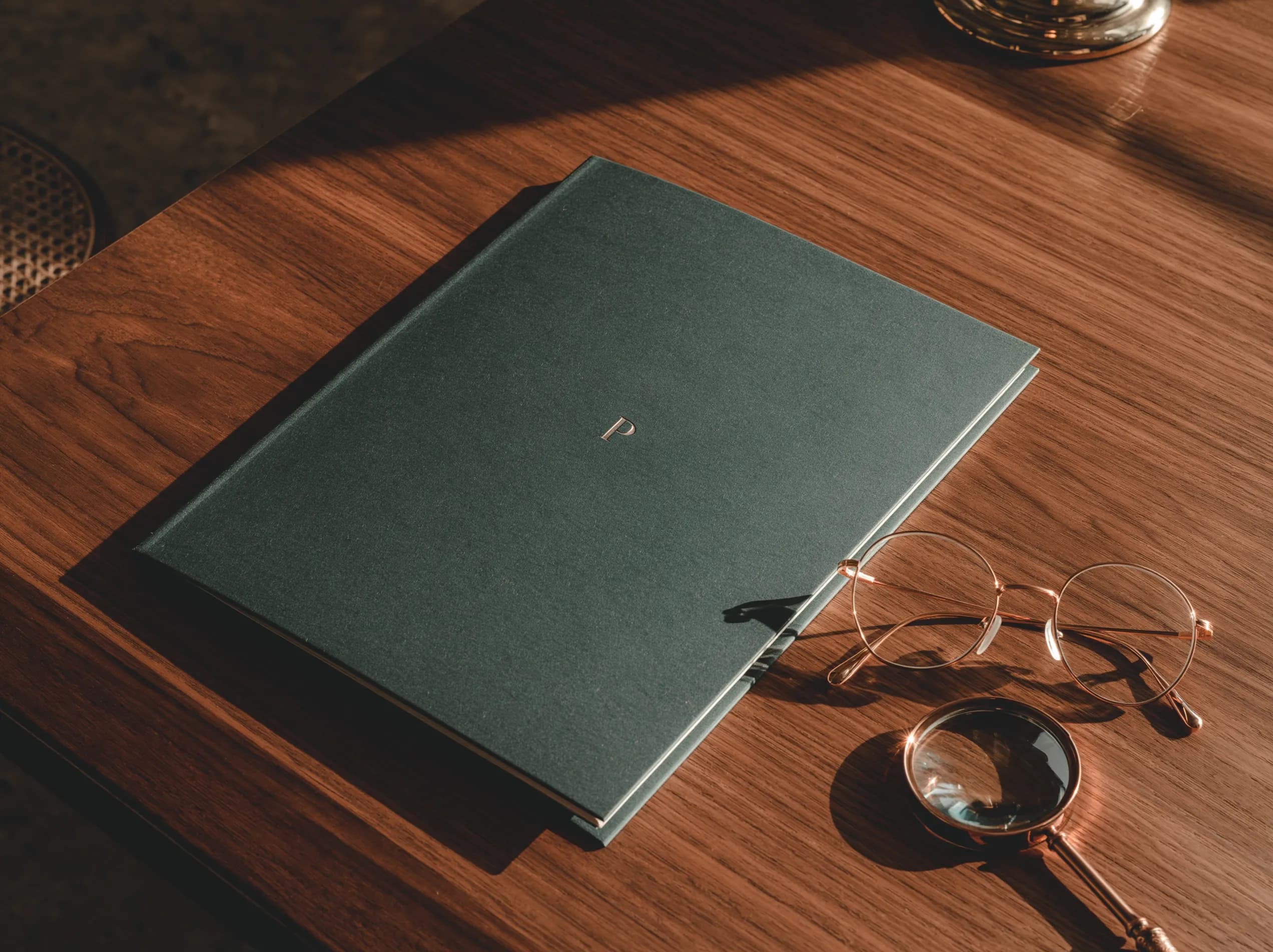 Forest-green compliance folder with reading glasses and magnifying glass